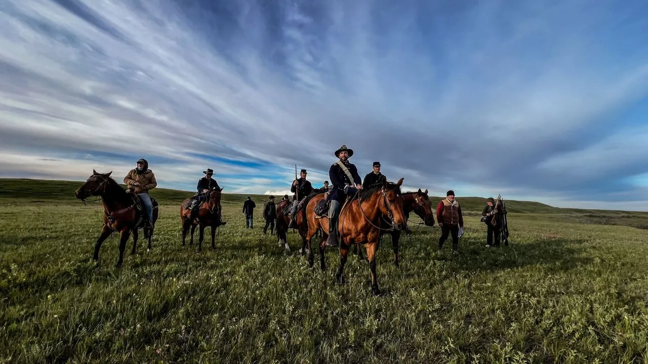 grupo de jinetes en medio de un amplio paisaje natural